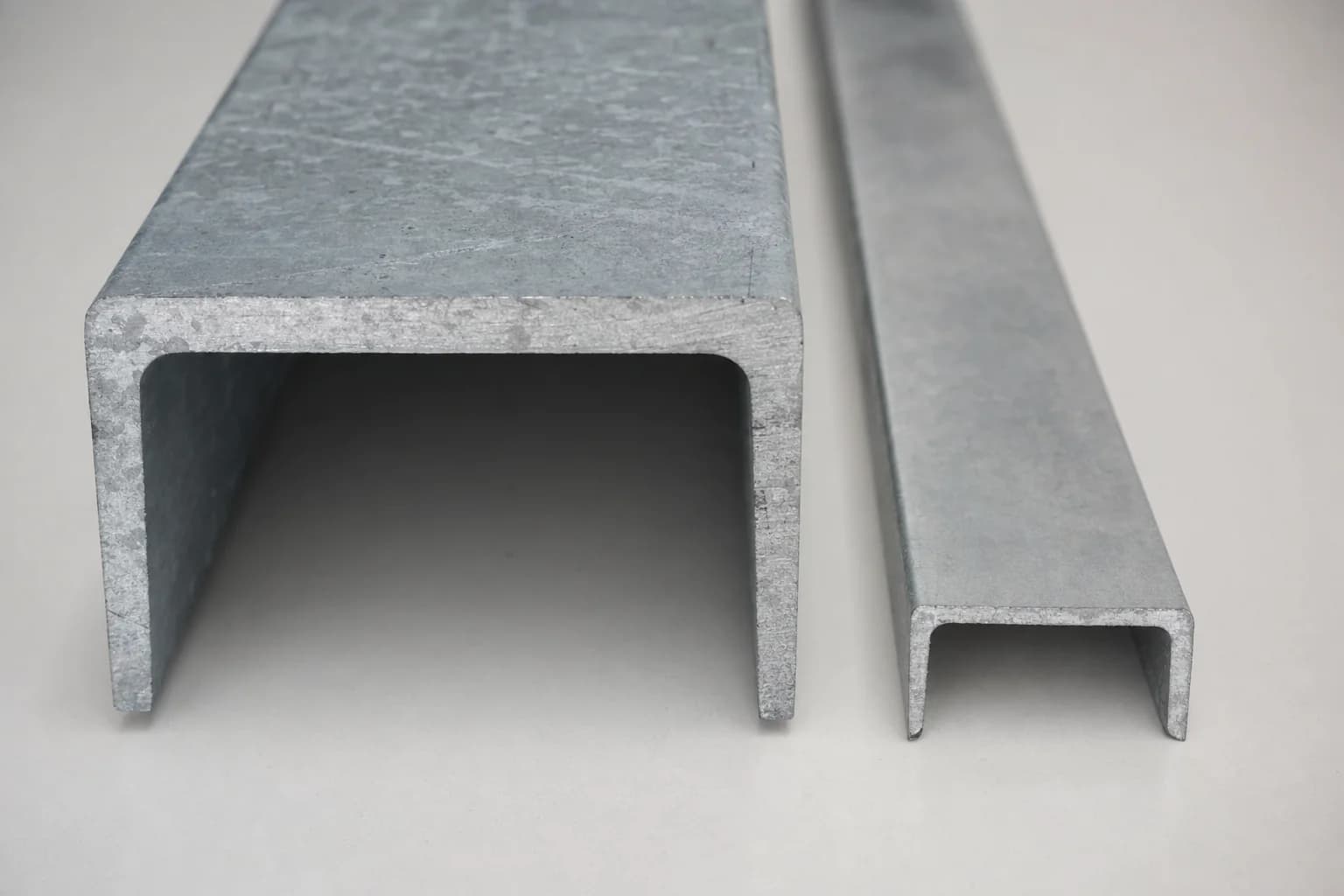Premium thick hot-dip galvanised Australian-made structural steel section laid against a thinner imported steel section on a clean neutral surface